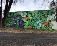 street view of a mural with green leaves, butterflies, and purple flowers