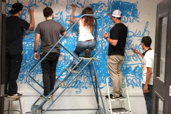 4 people painting on a wall.
