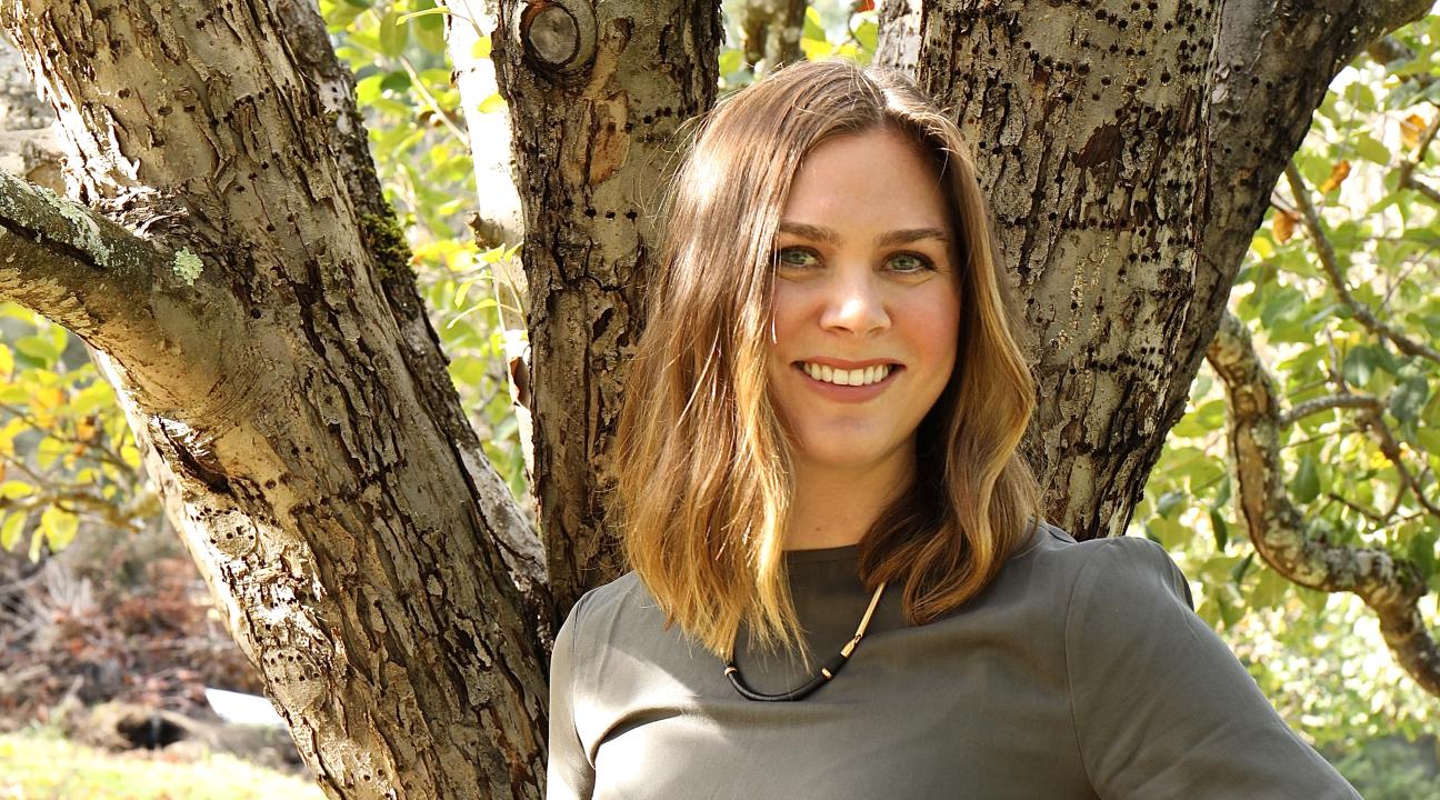 Kara de Lambert with hand on hip standing in front of a tree