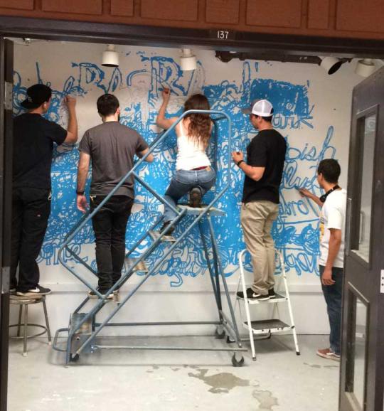 4 people painting on a wall.