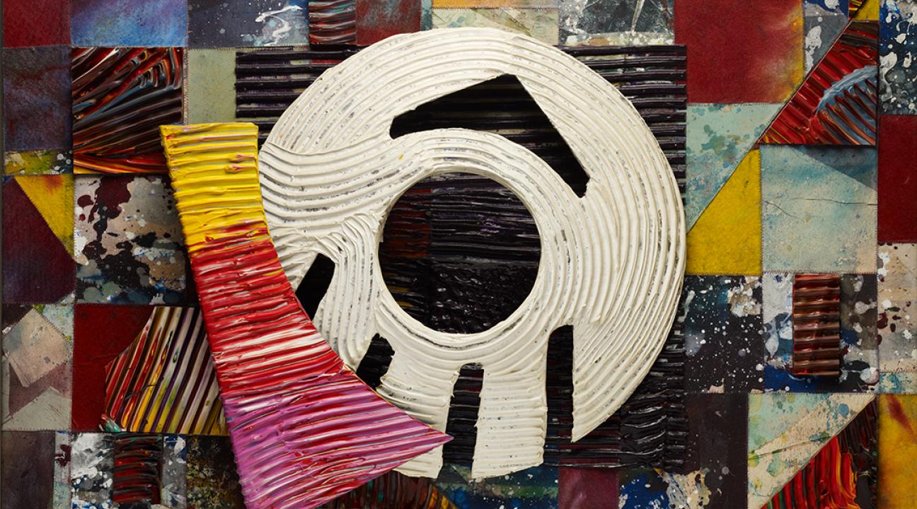 Abstract mixed-media artwork featuring a collage of colorful geometric shapes in red, yellow, blue, and maroon tones. At the center is a large white circular form with black angular markings resembling an eye or target. The piece combines layered textures and dynamic color contrasts, creating a sense of rhythm and motion