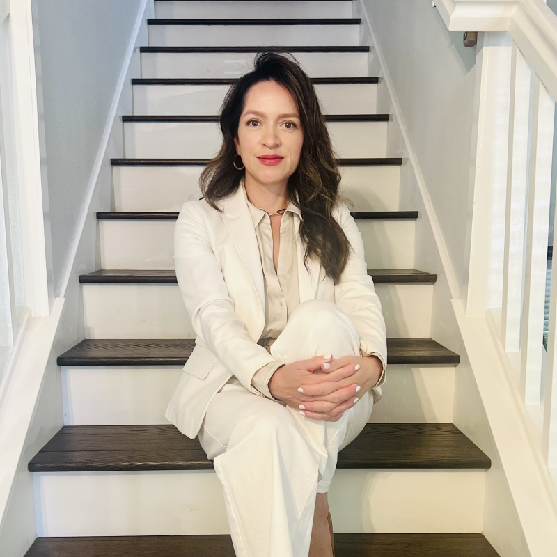 Claudia Molloy sitting on stairs in a white suit